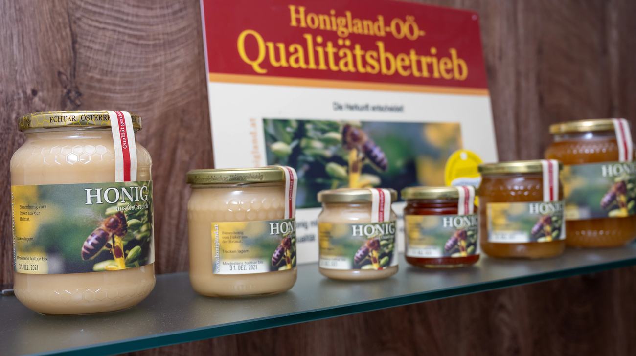 Honiggläser verschiedener Größen im Verkaufsregal des Hofladens